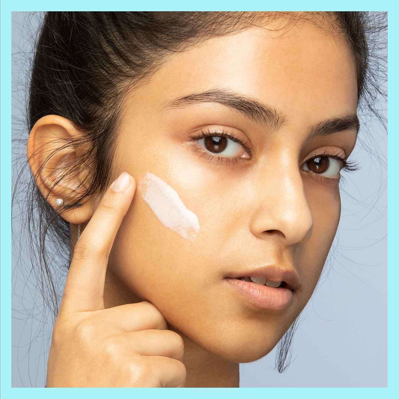 Woman applying primer on her face